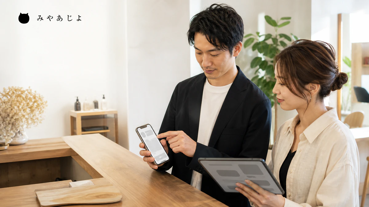 美容室の担当者がスマートフォンの予約導線を確認するイメージ