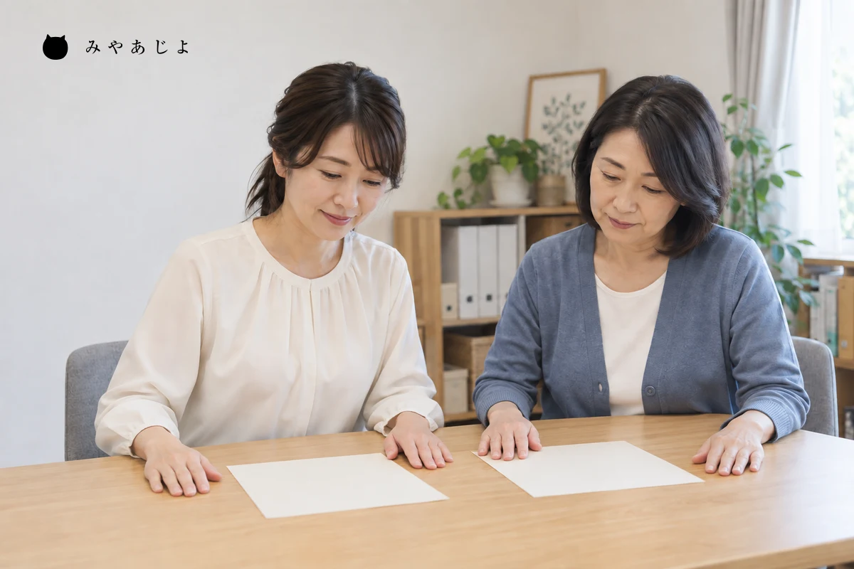 架空の在宅福祉事業所の担当者二人が白紙の案内用紙を並べ、相談後の連絡と資料の説明を照合する編集イメージ