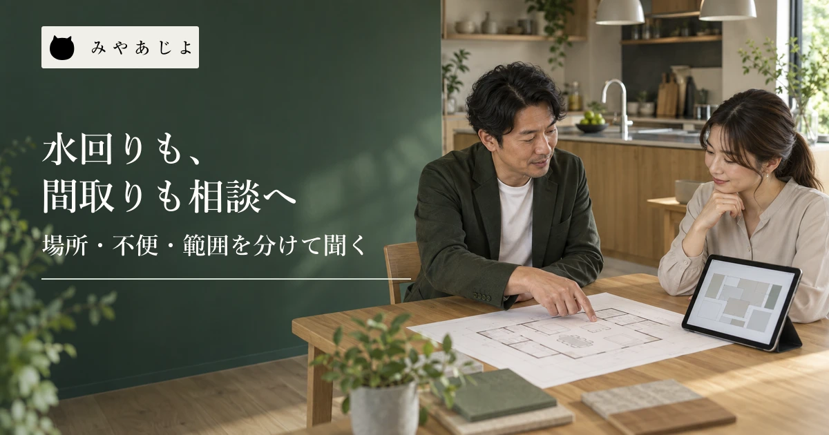 住宅リフォーム担当者とWeb担当者が台所を背景に間取り図とタブレットを見ながら相談する場面
