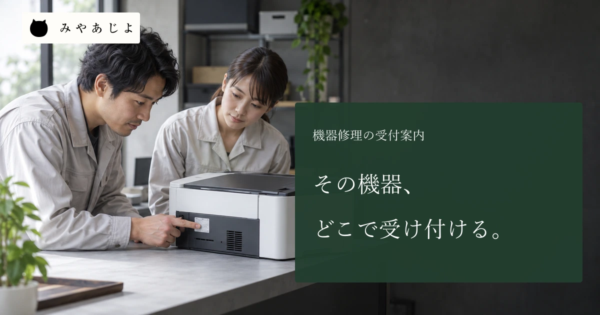 修理会社で成人の受付担当者二人が無標識の機器の外観を確認する場面