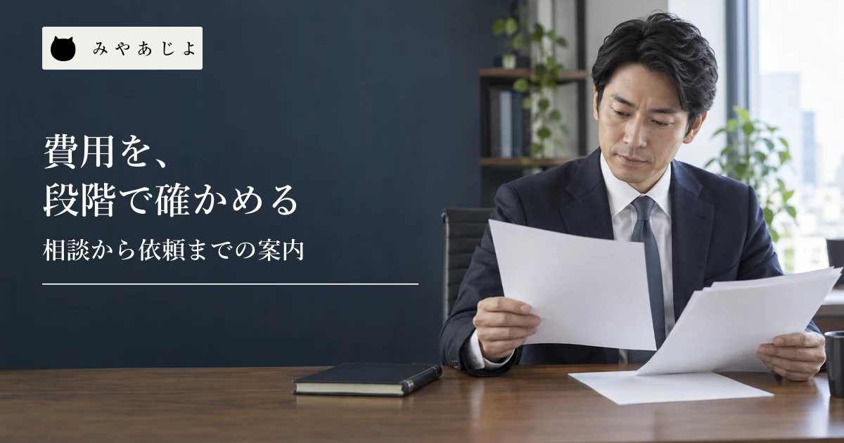 事務所の担当者が無記名の書類を見比べている場面