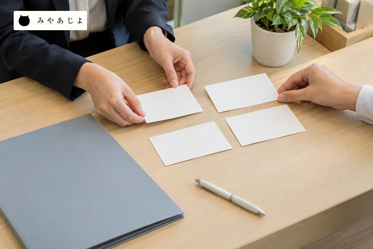 障害福祉事業所で成人の受付担当者二人が無記名の見学案内資料を机上で確認する場面