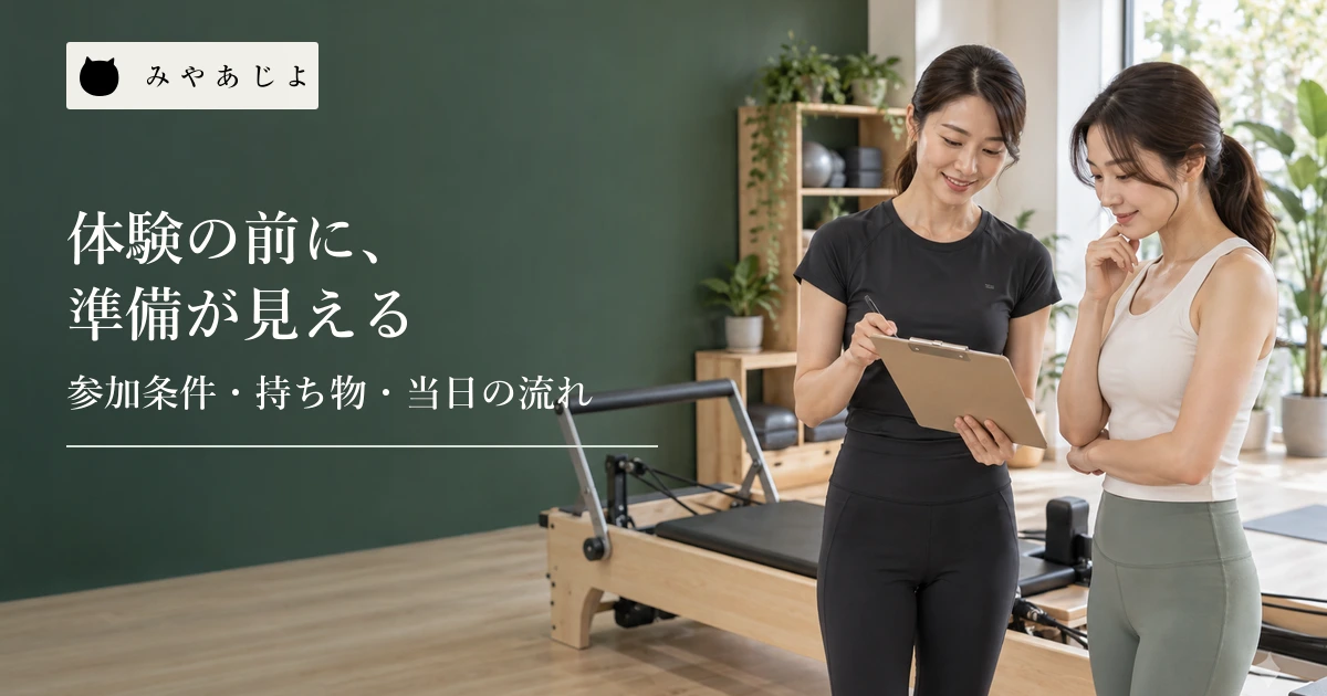 ピラティススタジオで指導者が初回体験の案内を来訪者と確認する場面