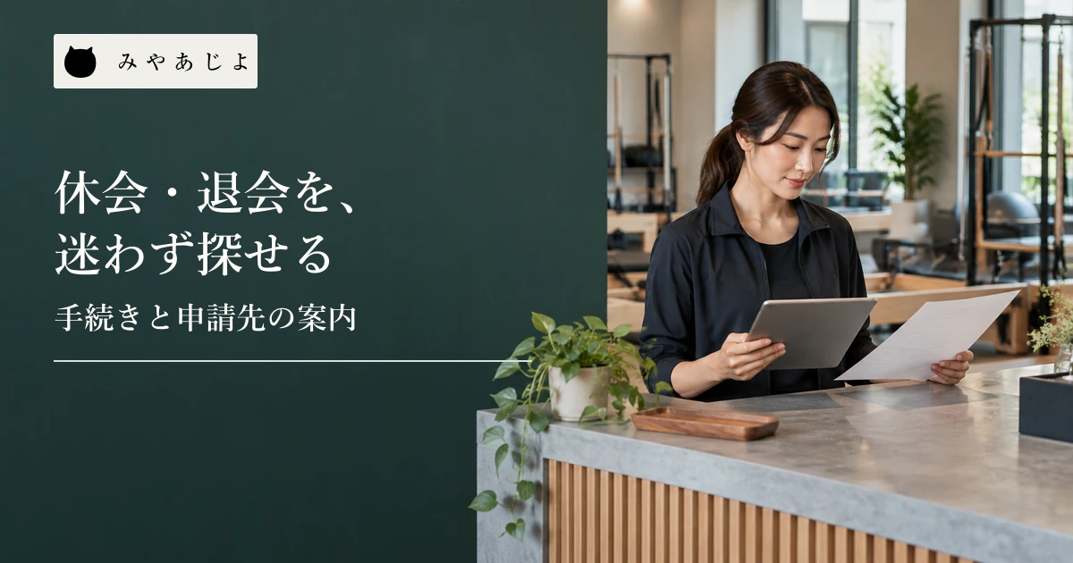 ジムの担当者が受付で会員向けの案内資料とタブレットを見比べる場面