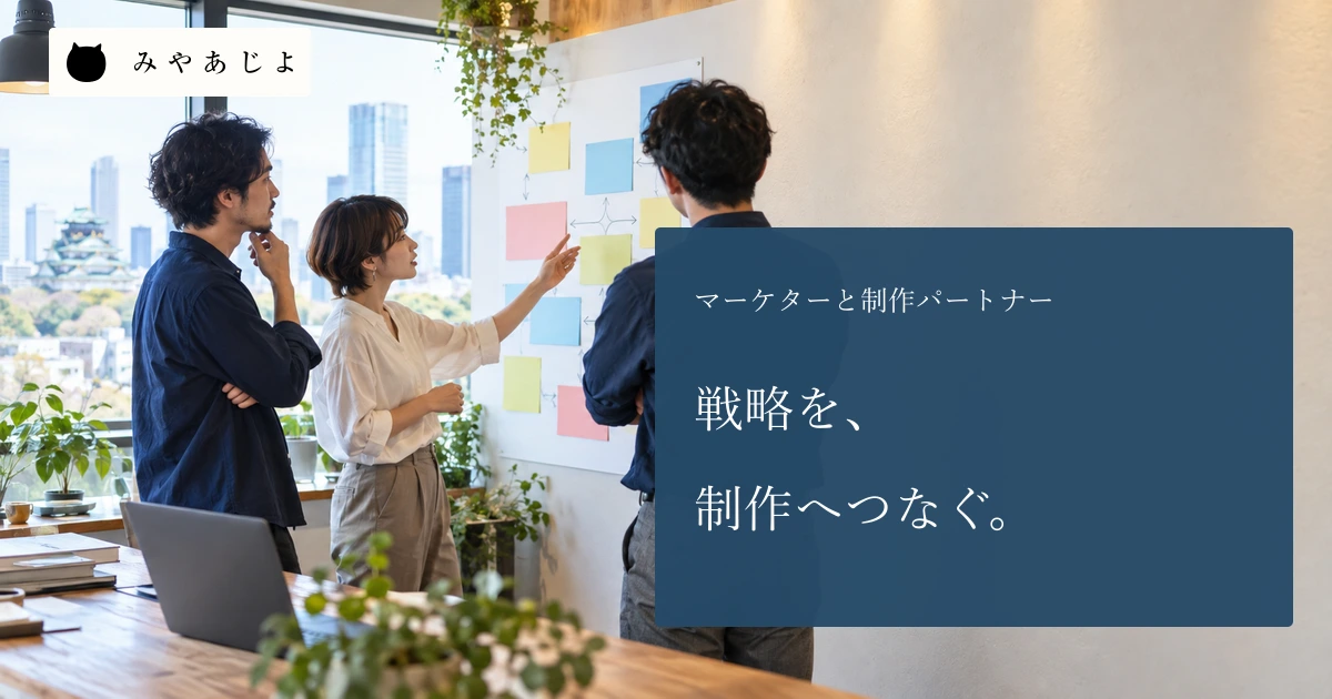 Web制作打ち合わせで成人三人が文字のない掲示板を見ながら施策と制作物を確認する場面