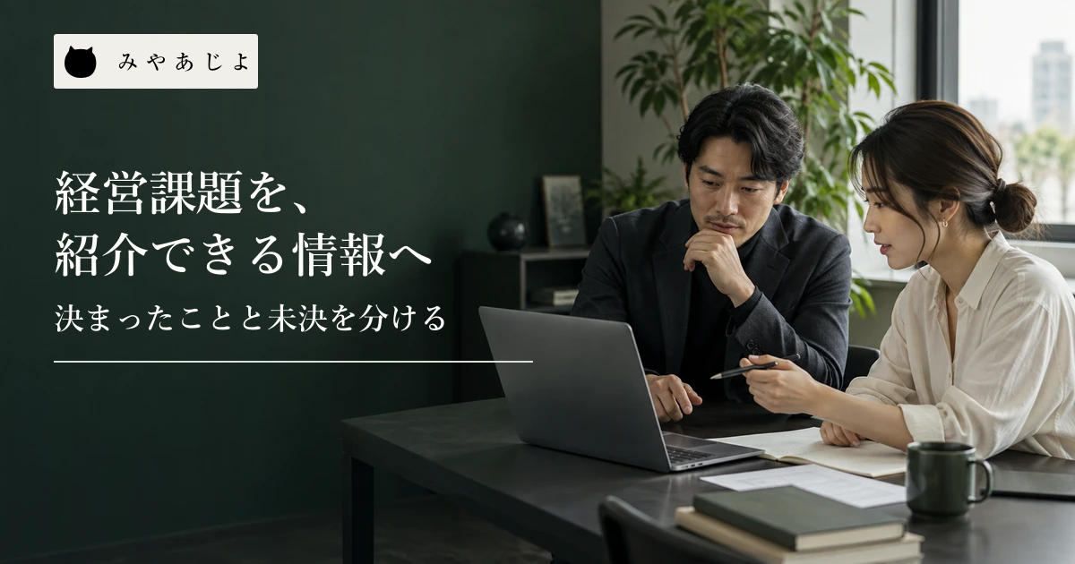 コンサルタントとWeb制作担当者が机を囲み、案件の資料とノートパソコンを確認する場面