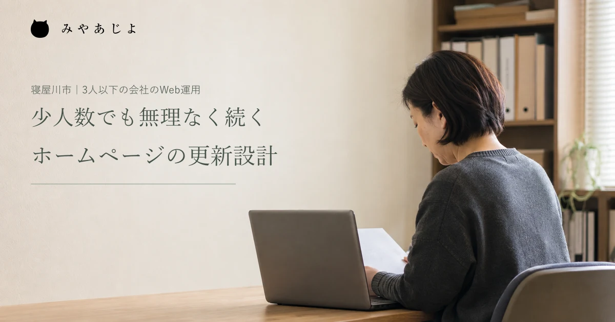 架空の小規模企業の担当者が机で案内資料と端末を確認する編集イメージ