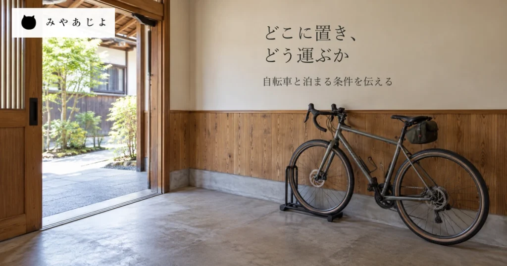 架空の宿の入口脇の自転車用室内区画と出入口への通路に、自転車の保管場所と運ぶ道を案内する見出しを添えた一般的な宿泊イメージ