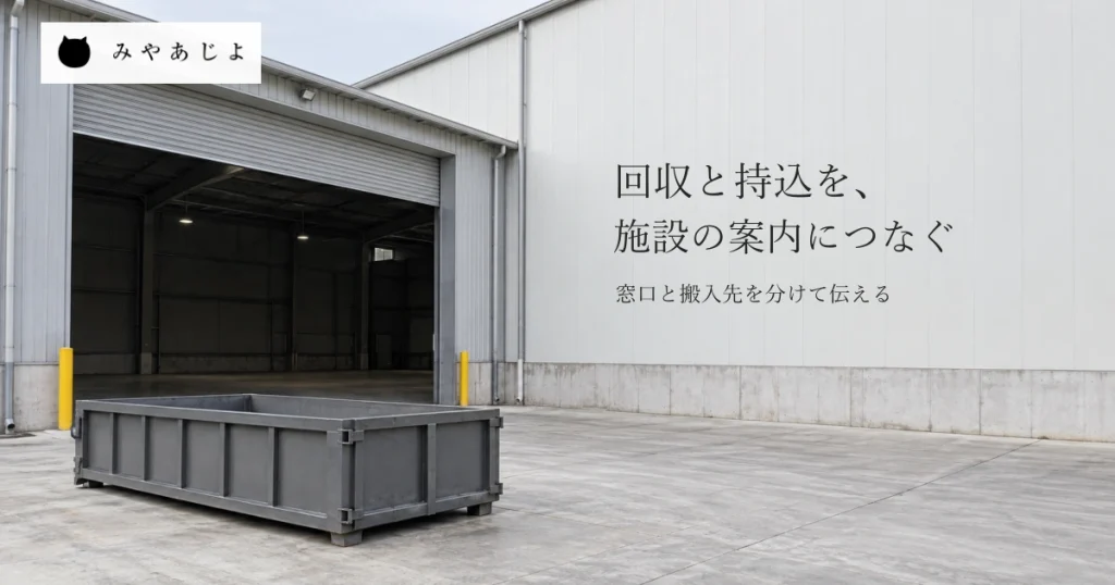 普通の受入施設を想定した建物の搬入口と手前の空の無地の金属製コンテナを前庭から見通し、回収と持込の相談先・搬入先を考える自然な写真イメージ