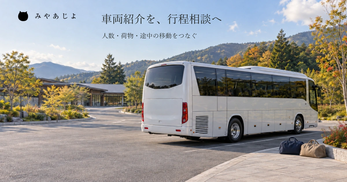 普通の見学施設を想定した乗降場所の無記名の貸切バスと二つの旅行バッグを自然な昼光で広く見せ、団体の一日の行程を相談する写真イメージ
