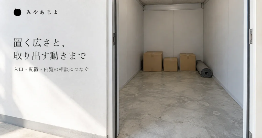 実寸の収納室を開いた入口から見て、壁際の重ねていない箱と巻いたマット、出し入れを考えるための空いた床を見せる自然な写真イメージ