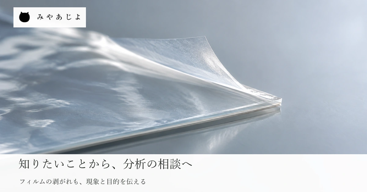 普通の台の上の一部が剥がれた一般的な透明フィルムを自然な光と実物の素材感で見せ、装置名が未定でも現象と目的から分析の相談を考える写真イメージ