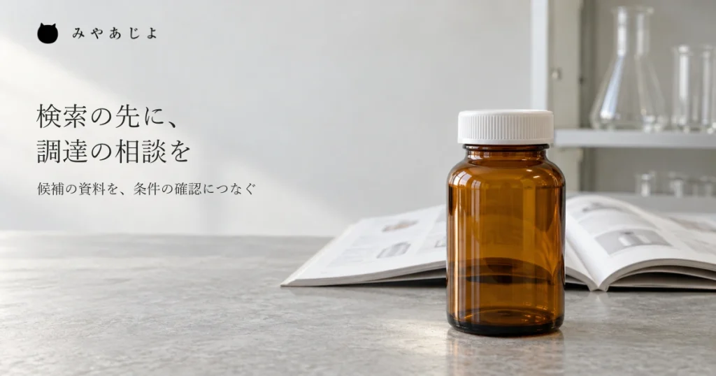 研究用品の商社の仕事場を想定し、閉じた無地の茶色いガラス容器と開いたカタログを近くで見せ、未掲載品の候補資料から調達相談を考える自然な写真イメージ