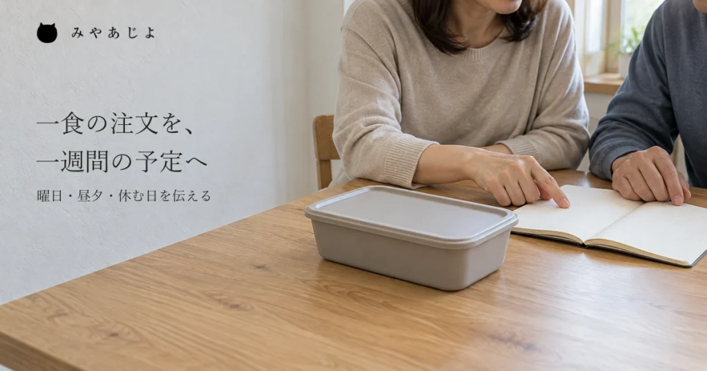 家庭の食卓で閉じた一食分の配食容器のそばのノートを二人の成人の手が確かめ、本人と家族が同じ配達予定を考える自然な写真イメージ