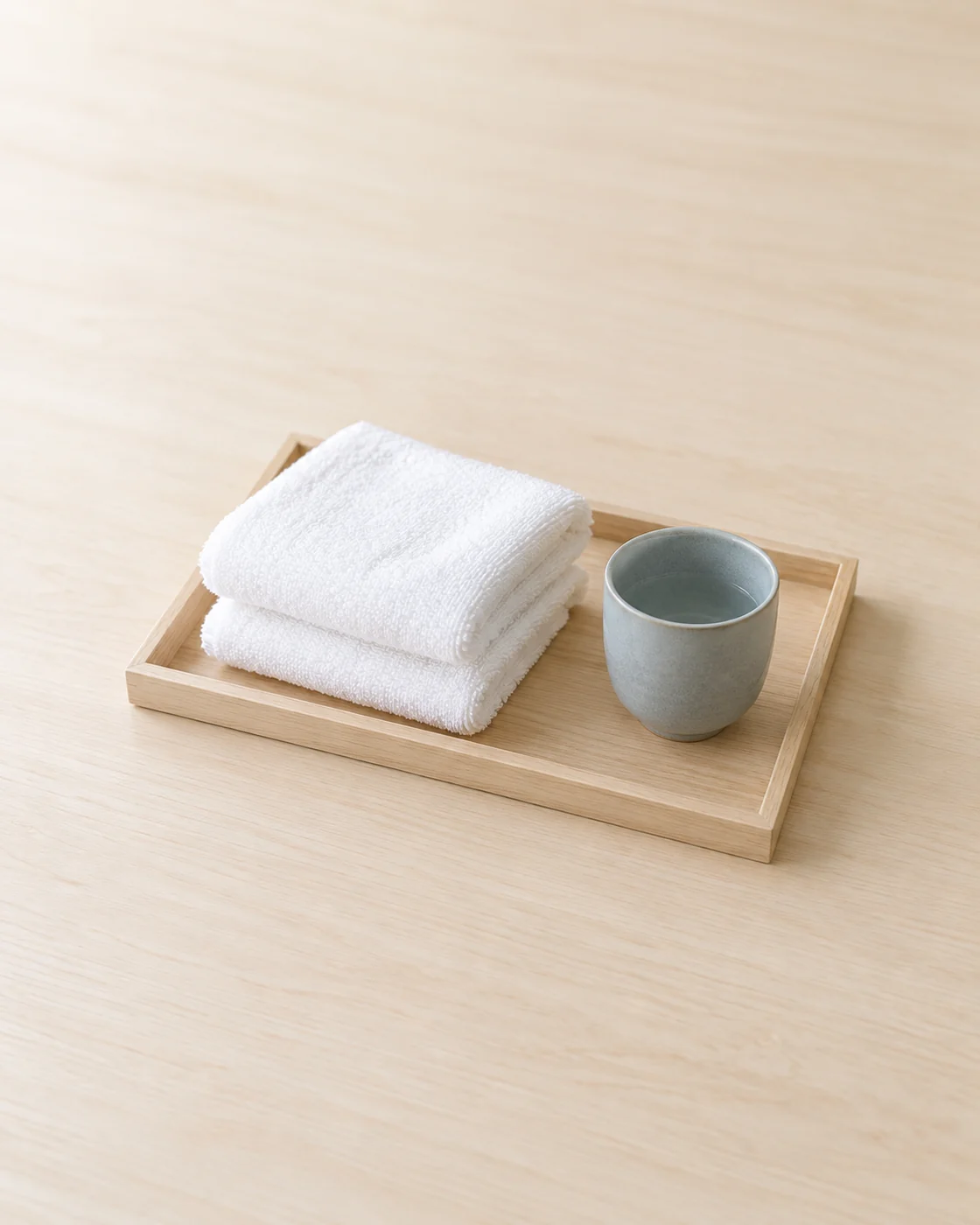 木のトレーに畳んだタオル2枚と湯飲みを置いた生成イメージ