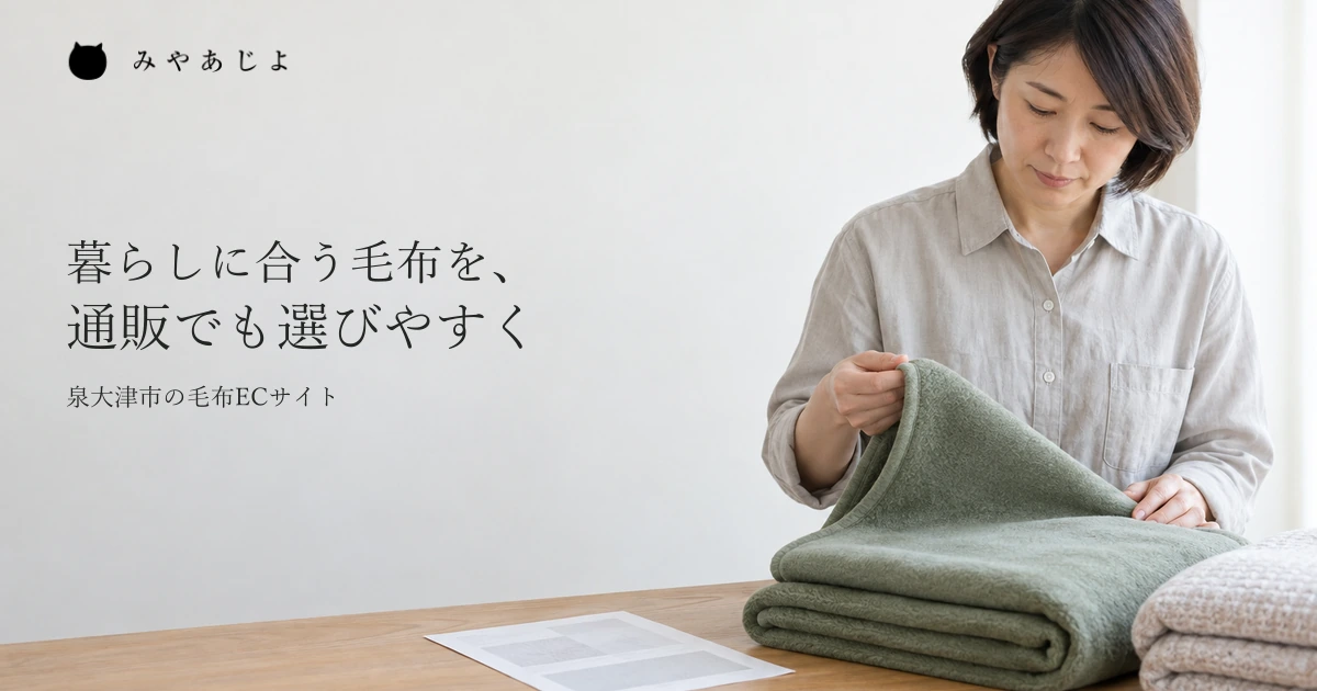 販売担当者が畳んだ毛布の一端を持ち、質感を確かめる一般的な作業イメージ