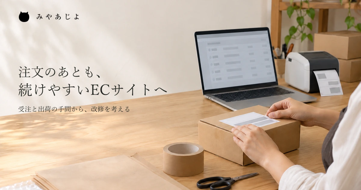 注文画面と出荷用の箱を確かめながら、ネットショップの発送を準備する机上のイメージ
